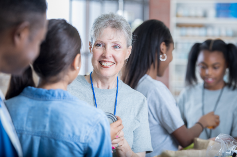 Smiling older woman wearing lanyard interacting with other event volunteers